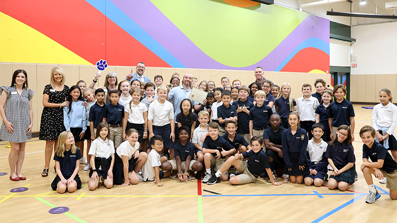 Indoor photo of a class of children and staff in the gym